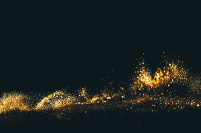 Close-up of gold glitter against black background