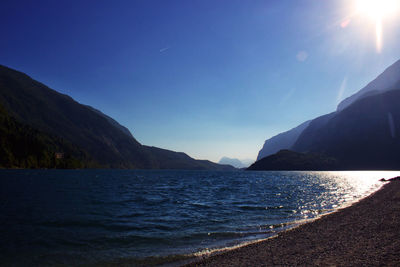 Scenic view of sea and mountains against blue sky