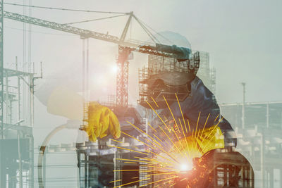 Digital composite image of crane at construction site against clear sky