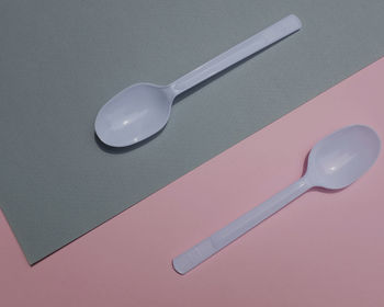 Flat lay a white plastic spoon on pink and gray paper background. minimal concept