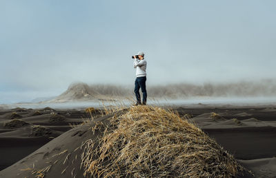 Full length of man photographing on snow covered land