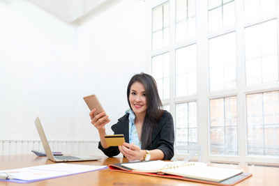 Young woman using mobile phone while sitting on table