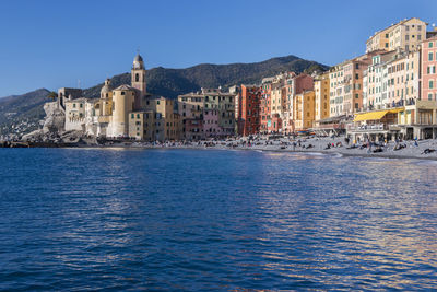 View of buildings by sea against blue sky