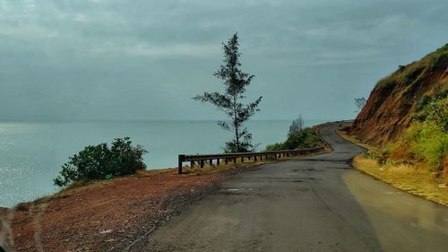 Empty road by sea against sky