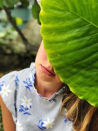 Close-up of woman hiding behind leaf