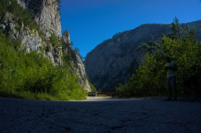 Rear view of man standing by road against mountain