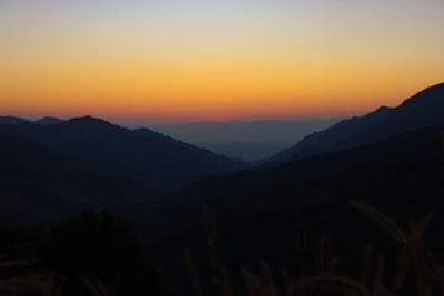 Scenic view of silhouette mountains against orange sky