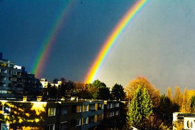 Rainbow over buildings in city against sky