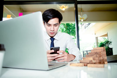 Mid adult man using mobile phone at table