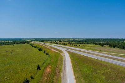 Panoramic view of road amidst field against clear sky