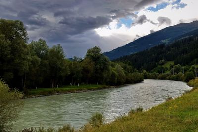 Scenic view of river by mountains against sky