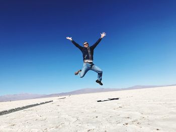 Man jumping in desert against sky