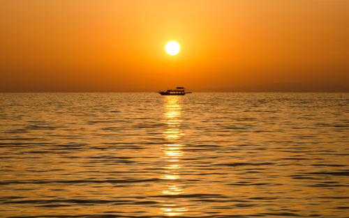 Boat sailing in sea at sunset