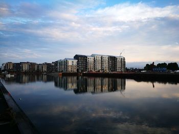 Reflection of buildings in lake against sky during sunset