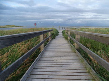 Road leading towards jetty against sky