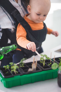 Baby girl gardening while being carried by mother at home