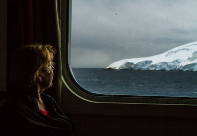 Woman looking through window while travelling in vehicle