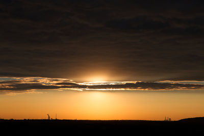 Scenic view of silhouette landscape against dramatic sky during sunset