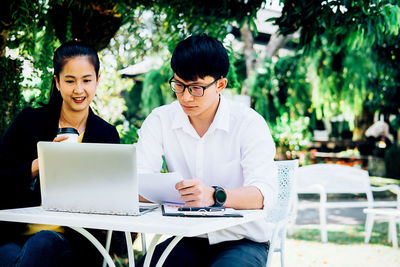 Business colleagues using laptop while sitting at outdoor cafe