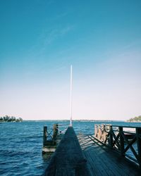 Pier over sea against clear blue sky