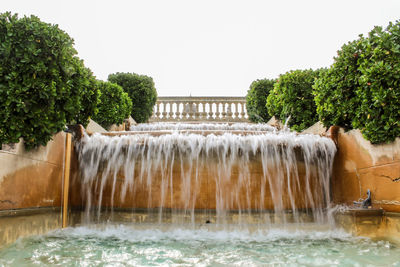 Water fountain against trees against clear sky