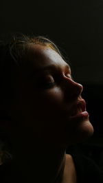 Close-up of young woman with eyes closed against black background