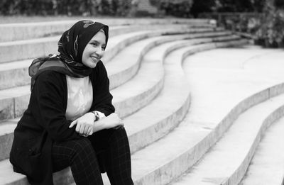 Smiling woman wearing hijab sitting on steps