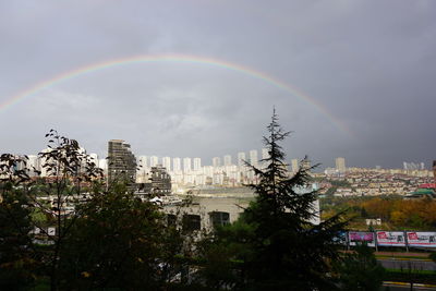 Rainbow over buildings in city against sky
