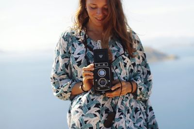 Young woman photographing against sky