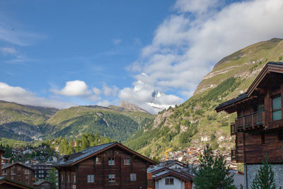 Houses in town by mountains against sky