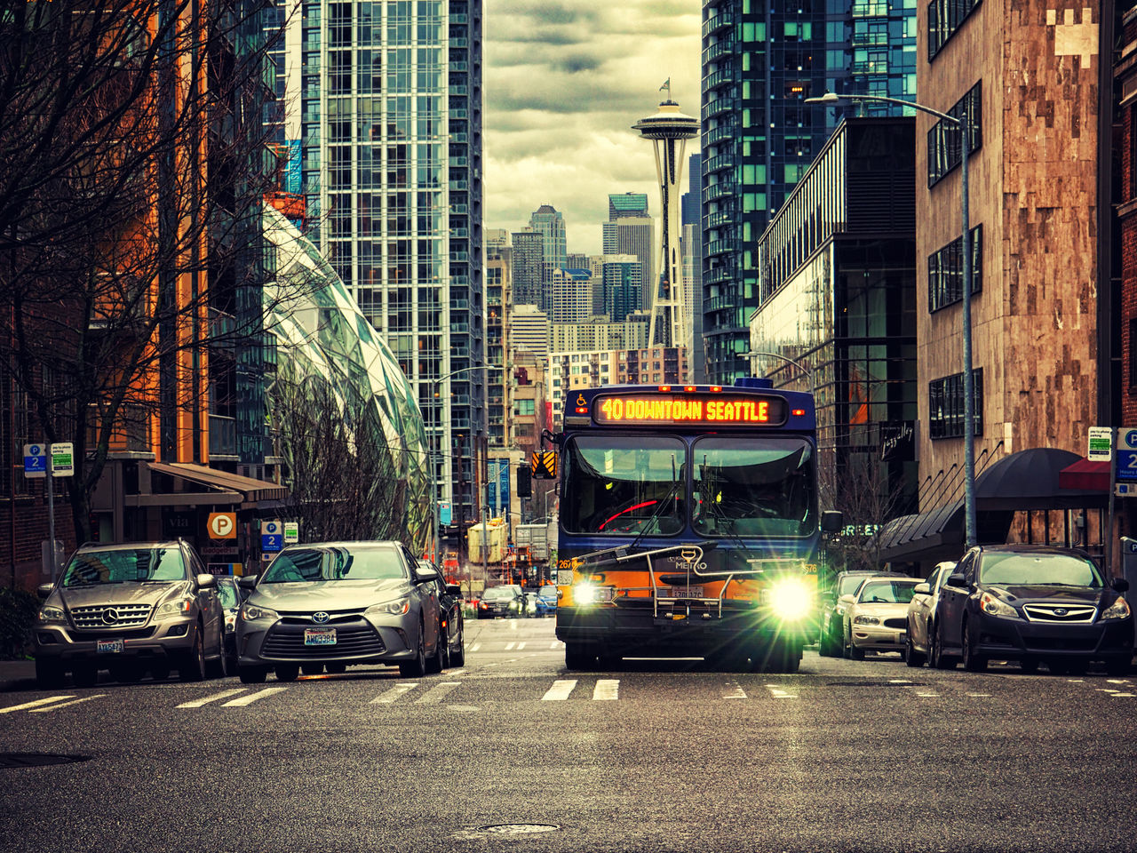 CARS ON ROAD BY BUILDINGS AGAINST SKY IN CITY DURING SUNSET