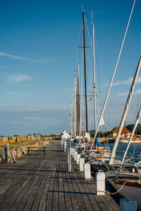 Boats moored by pier at harbor against sky