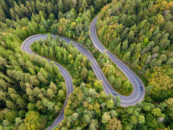 Winding road through the forest, from high mountain pass, in autumn season. aerial view by drone