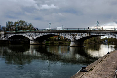 Bridge over river against cloudy sky