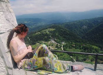 Woman looking at view while sitting on retaining wall