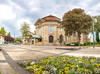 Street amidst plants and buildings against sky