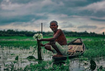 Man sitting on field against sky