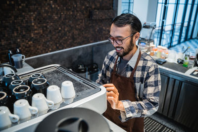 Smiling man preparing coffee in cafe