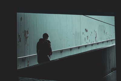 Silhouette man standing by railing against wall