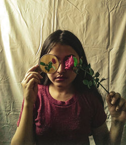 Girl holding flower in front of face against textile