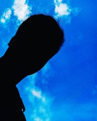 Low angle view of silhouette hand against blue sky