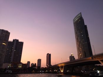 Illuminated modern buildings in city against sky during sunset