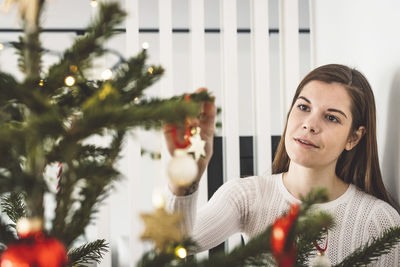 Portrait of young woman standing against christmas tree