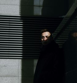 Portrait of young man standing against wall