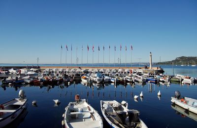 Boats moored at harbor against clear sky