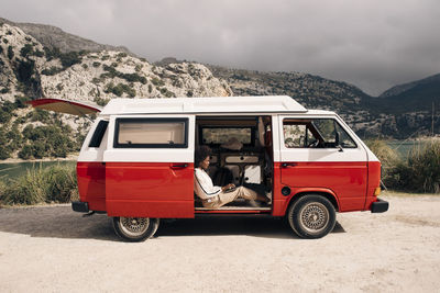 Side view of young woman using laptop while sitting in van