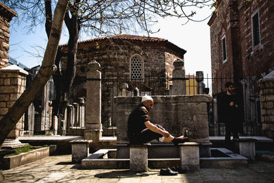 Man sitting outside temple against building
