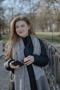 Portrait of young woman standing against trees
