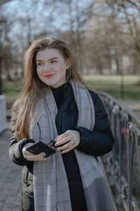 Girl with long hair in nature, looks slyly to the side, with red lipstick on her lips