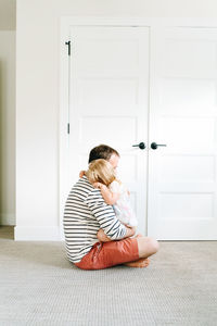 Side view of a father comforting a young daughter in a modern home